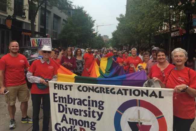 A large group of First Congregational UCC church members at the Pride Parade holding an "Embracing Diversity" banner