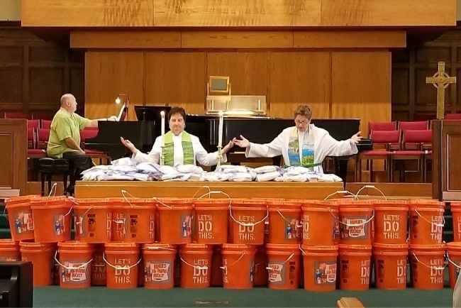 Ministers blessing five-gallon buckets filled with disaster supplies