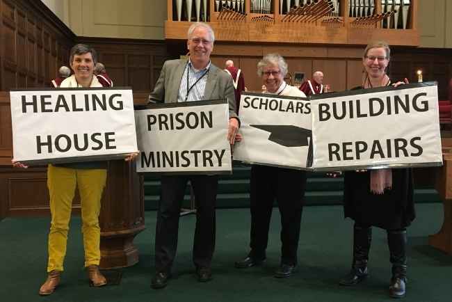 Four individuals holding signs that say: Healing House, Prison Ministry, Scholarships, Building Repairs